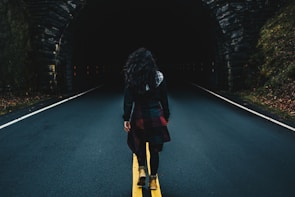 woman wearing black jacket walking on road