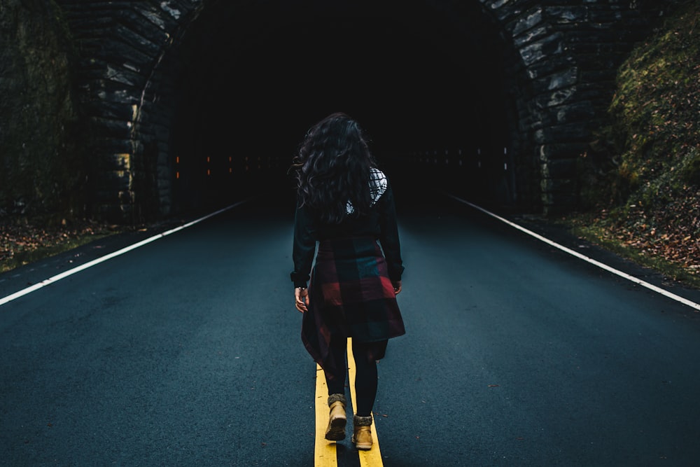 woman wearing black jacket walking on road