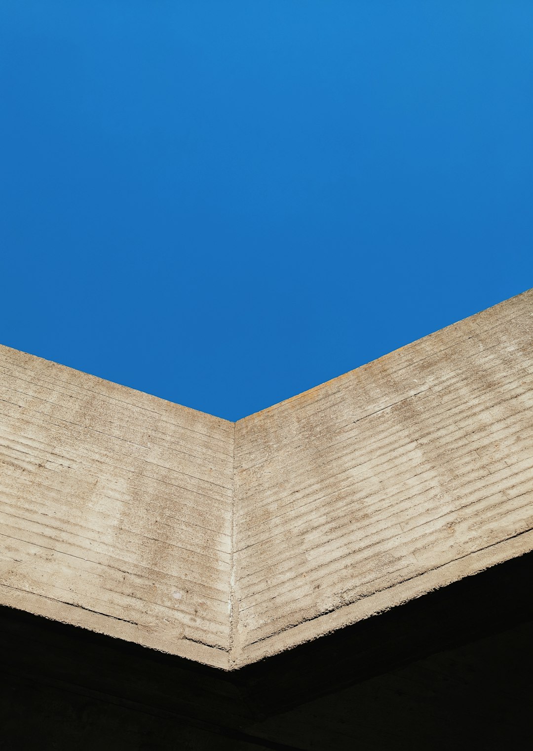 low-angle photography of gray concrete building under calm blue sky