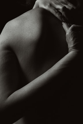 Black and white photo of hands gently massaging a shoulder.