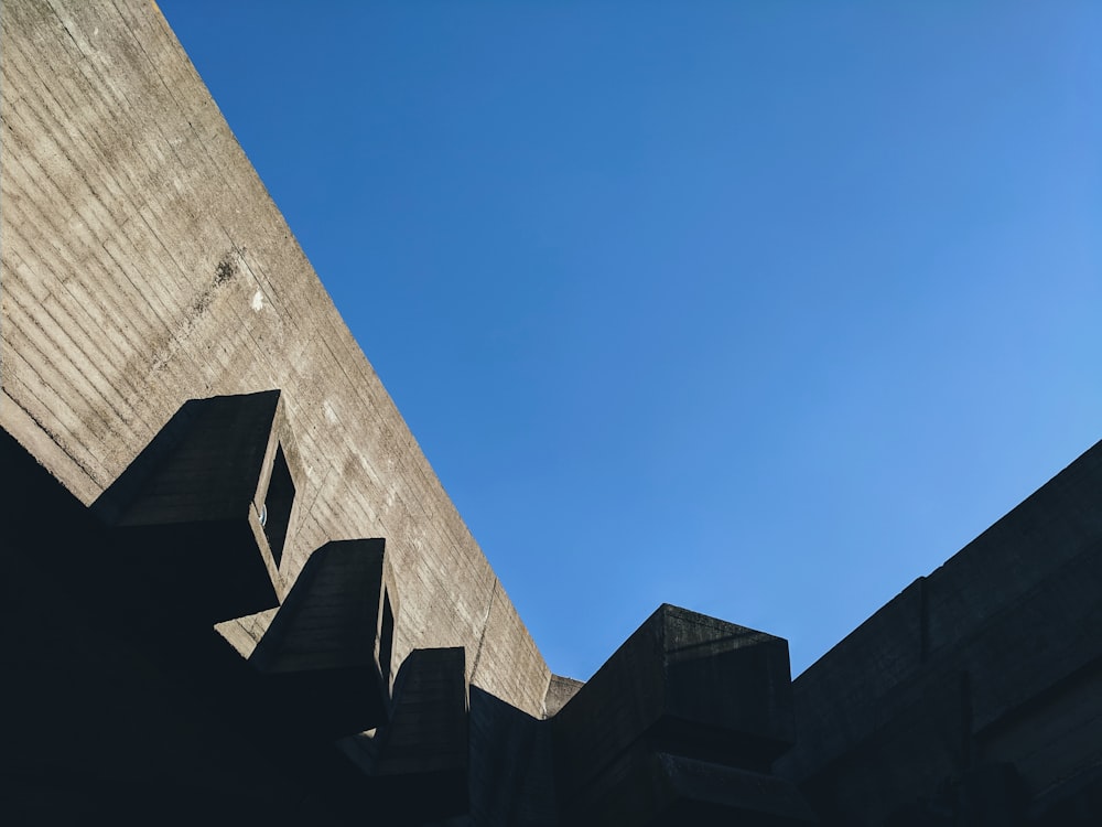 Low-Angle-Fotografie eines grauen Betongebäudes unter ruhigem blauem Himmel