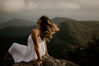 woman in white sleeveless dress sitting on hill
