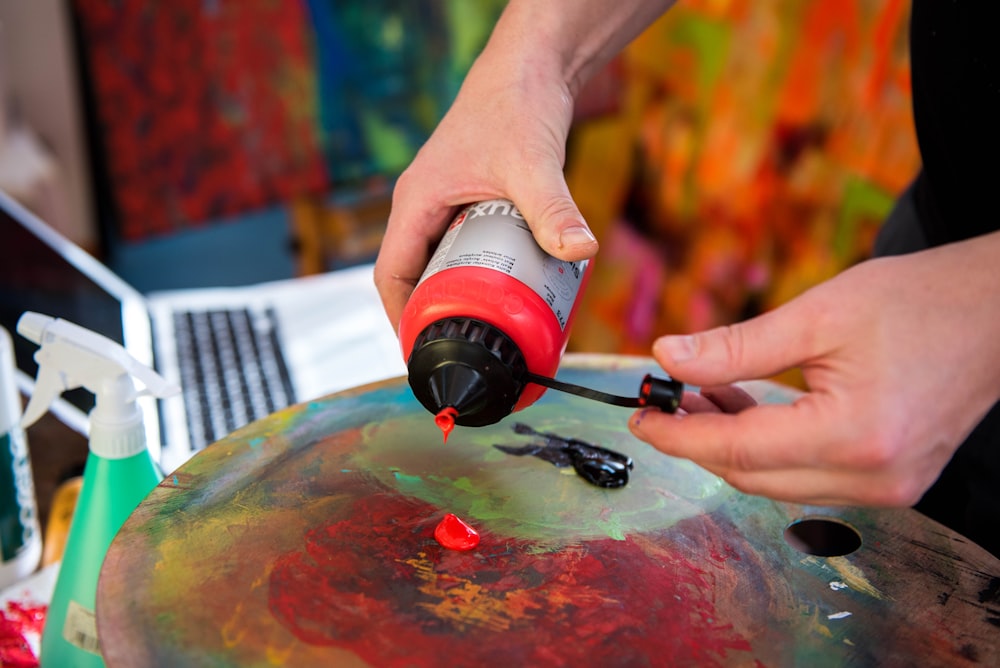 a person using a glue gun on a painting