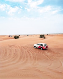 A luxury GMC Yukon driving through the majestic sandstone mountains of Al Ula under a clear blue sky.