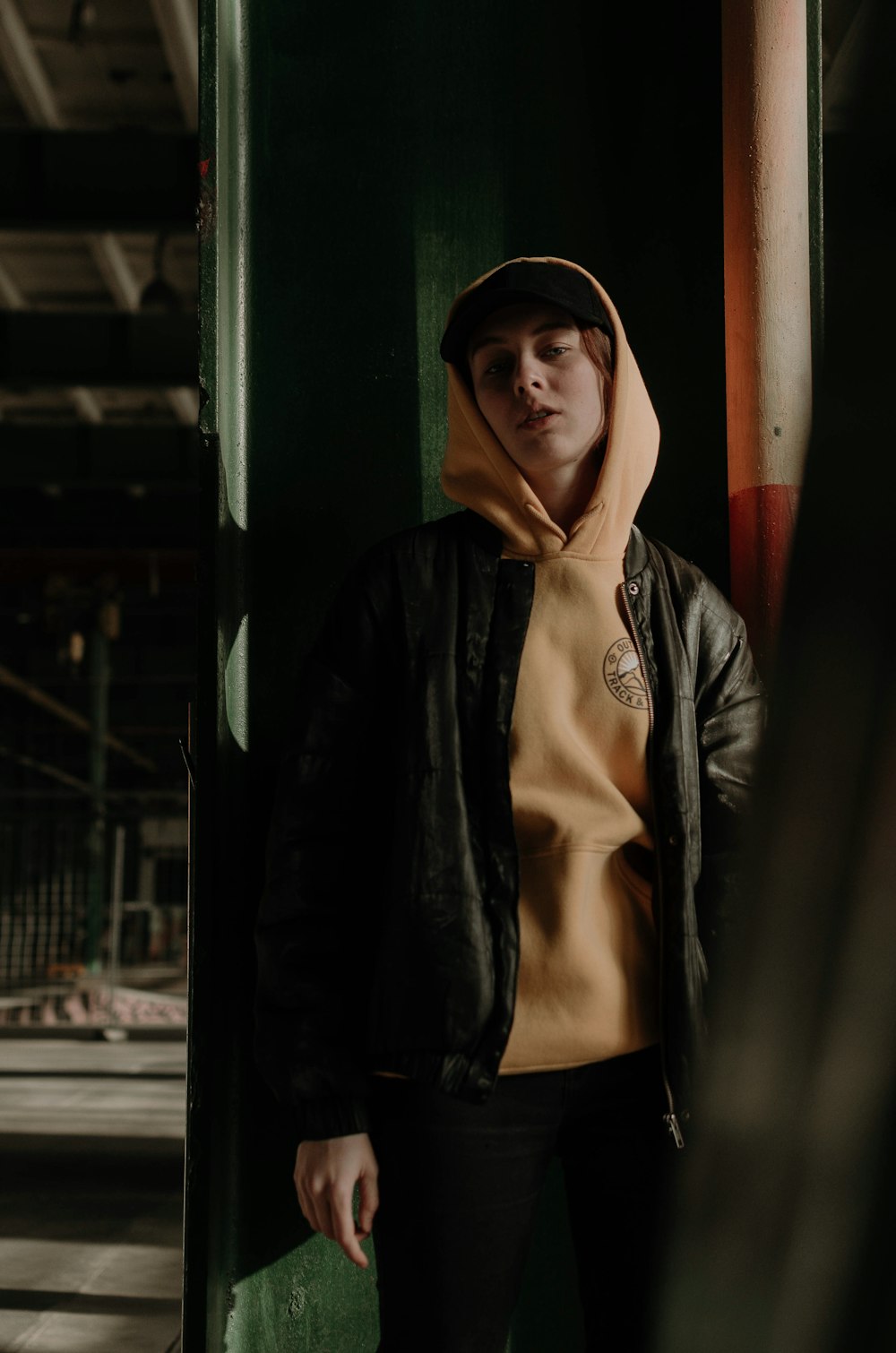 person in orange hoodie standing beside the wall