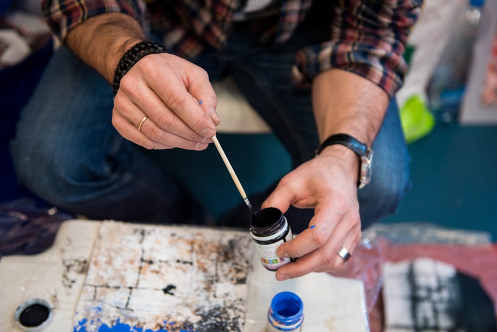 person holding paint bottle and paint brush