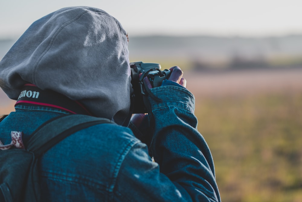 person in blue denim jacket taking photo