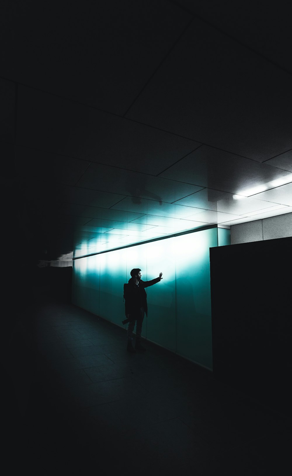 person standing beside white concrete wall