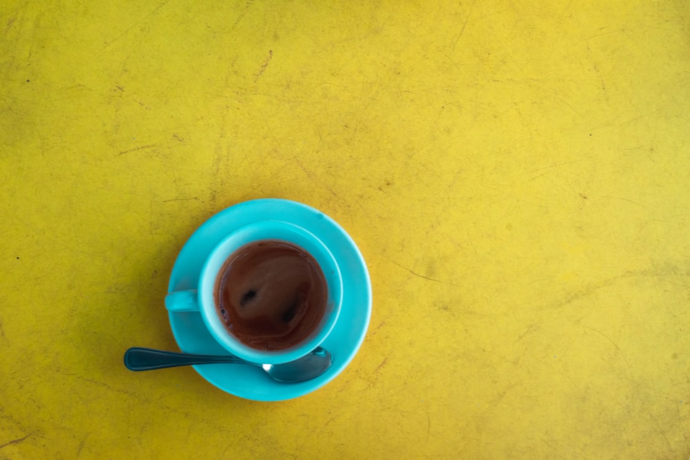 blue teacup with saucer on yellow surface