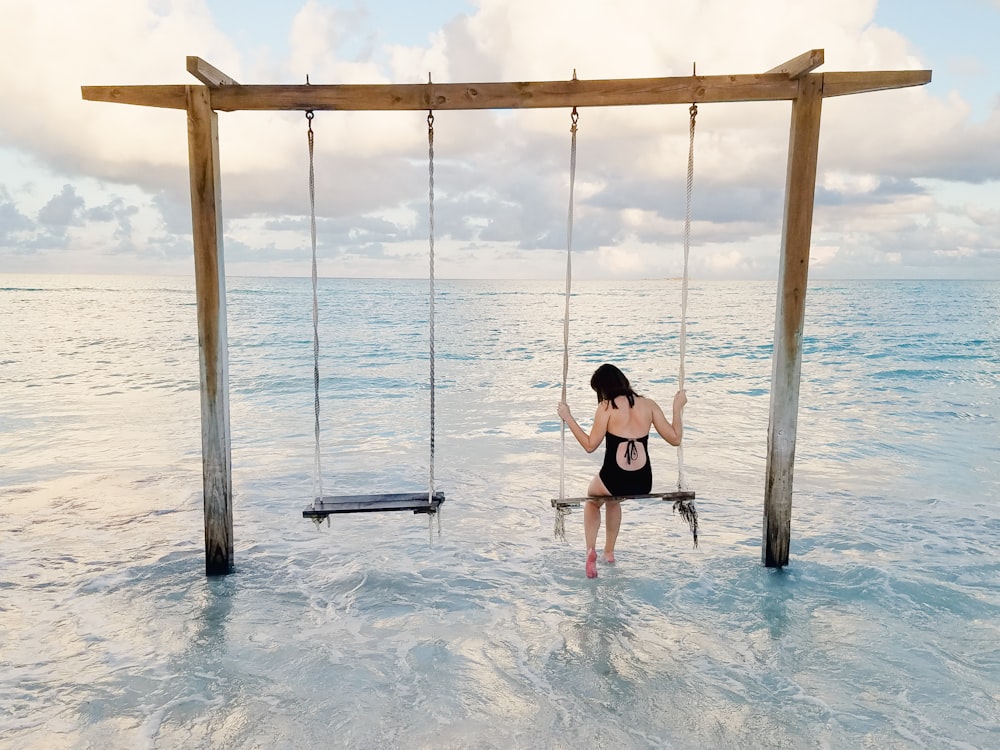 woman sitting on swing on body of water