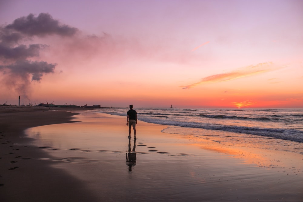 man standing on sea shore during golden hour