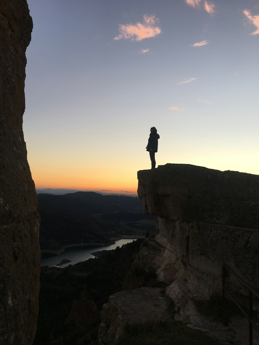 silhouette of woman standing on cliff