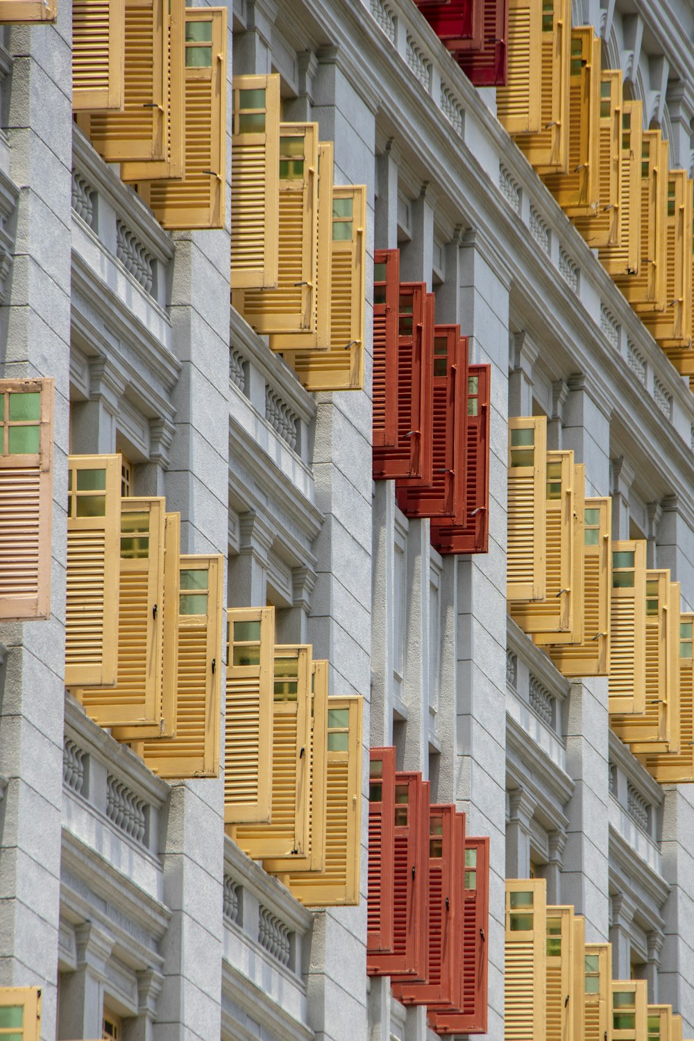 창문이 많고 노란색과 빨간색 셔터가 있는 건물