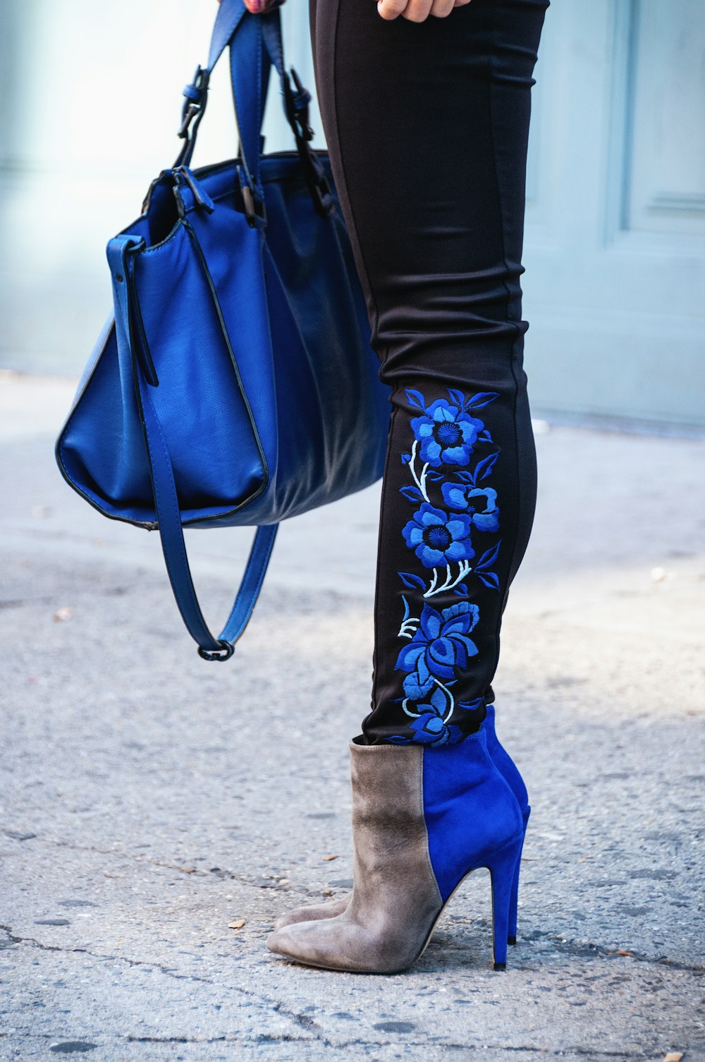 person in black leggings, booties and carrying blue bag