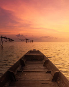 A rustic wooden boat docked by the Sri Lankan shore with nets full of freshly caught fish under a golden sunset.