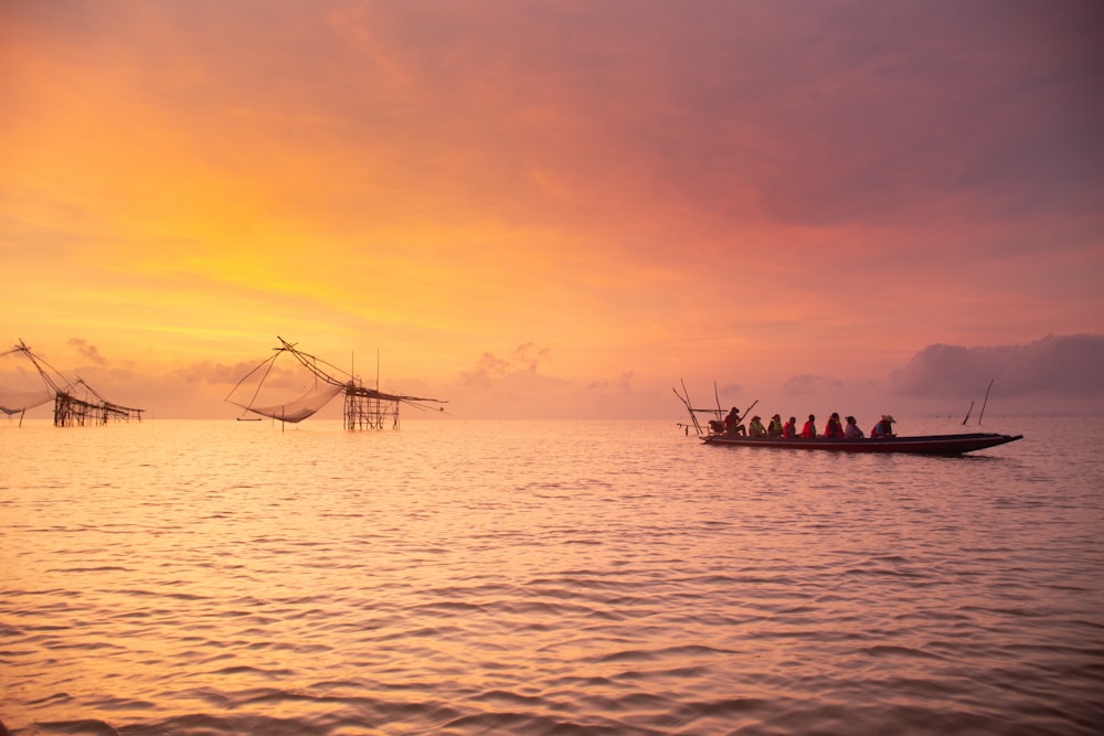 people riding on mini boat on sea during golden hour