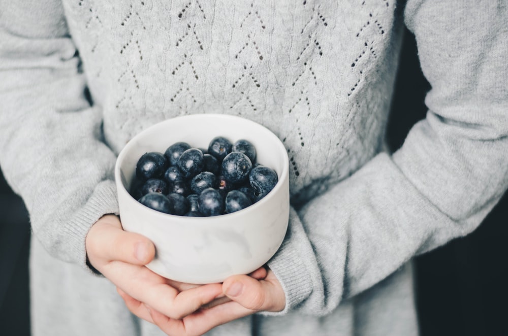 person holding bowl of grapes