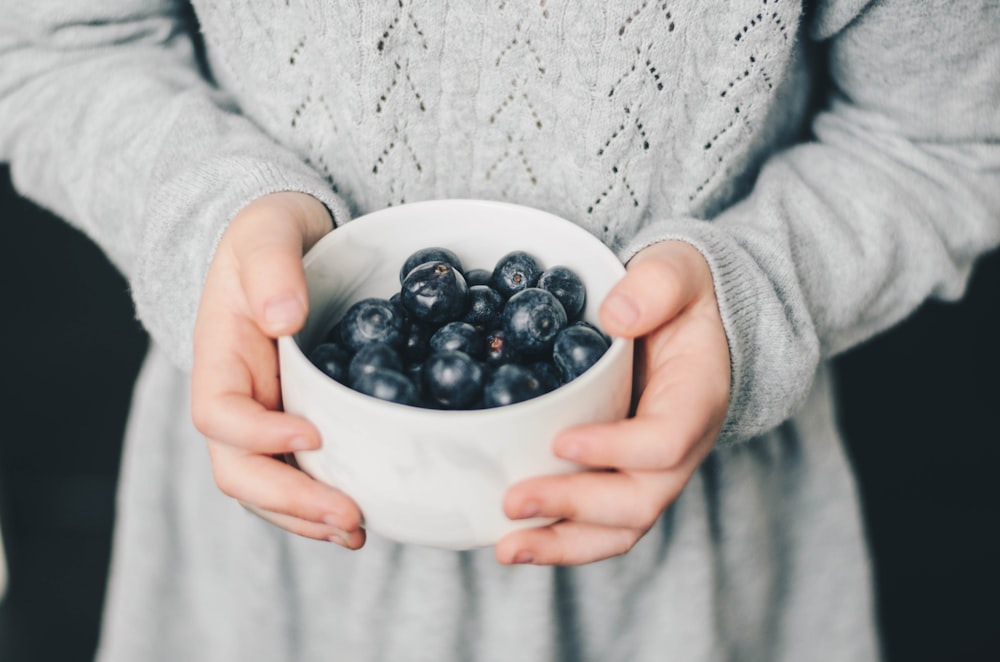 Frau trägt Schüssel mit Blaubeeren