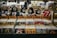 A vinyl record store display featuring cardboard cutouts of band members and symbols, with labeled sections for rock albums. Various album covers, including recognizable bands, are visible. The background shows more records and music memorabilia.