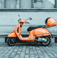 orange and black motor scooter parked on pavement