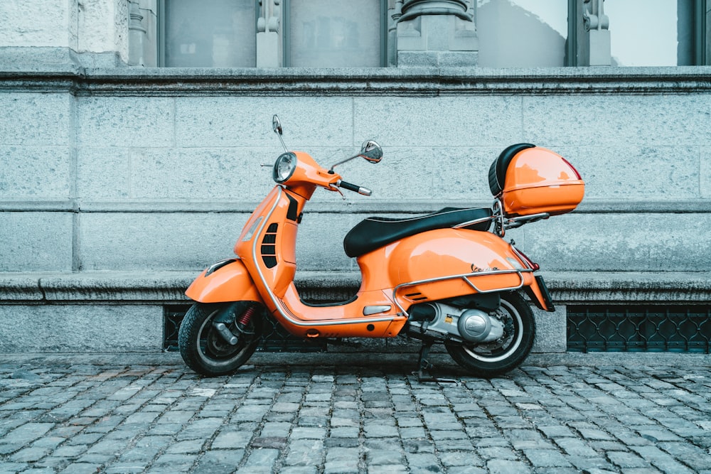 orange and black motor scooter parked on pavement