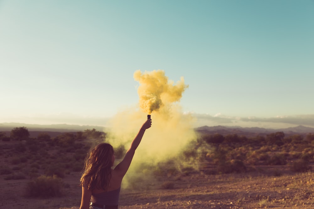 woman standing on desert holding flare