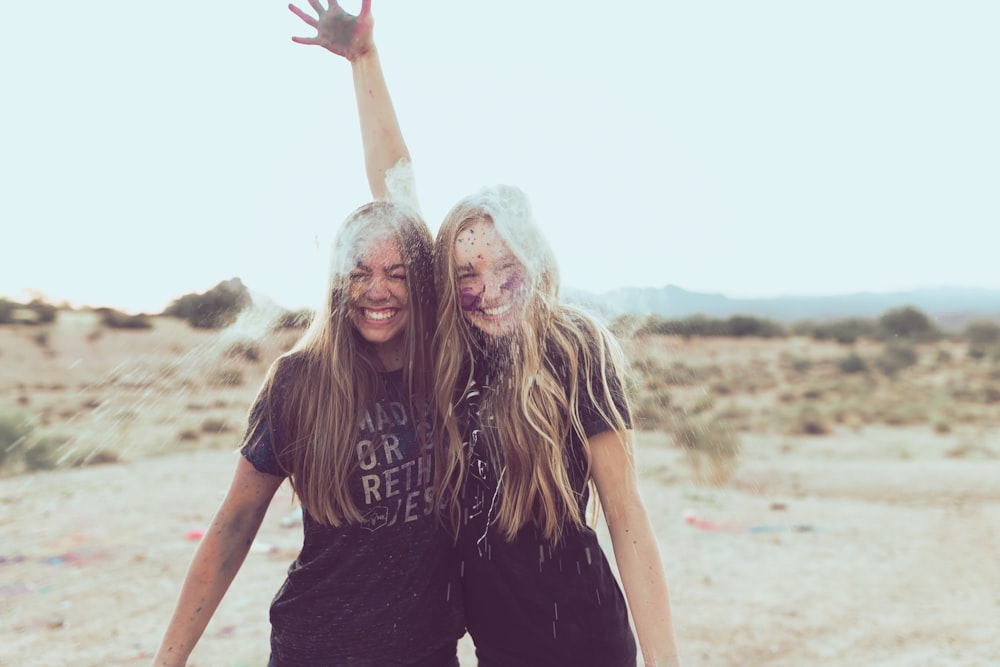 two woman smiling near grass