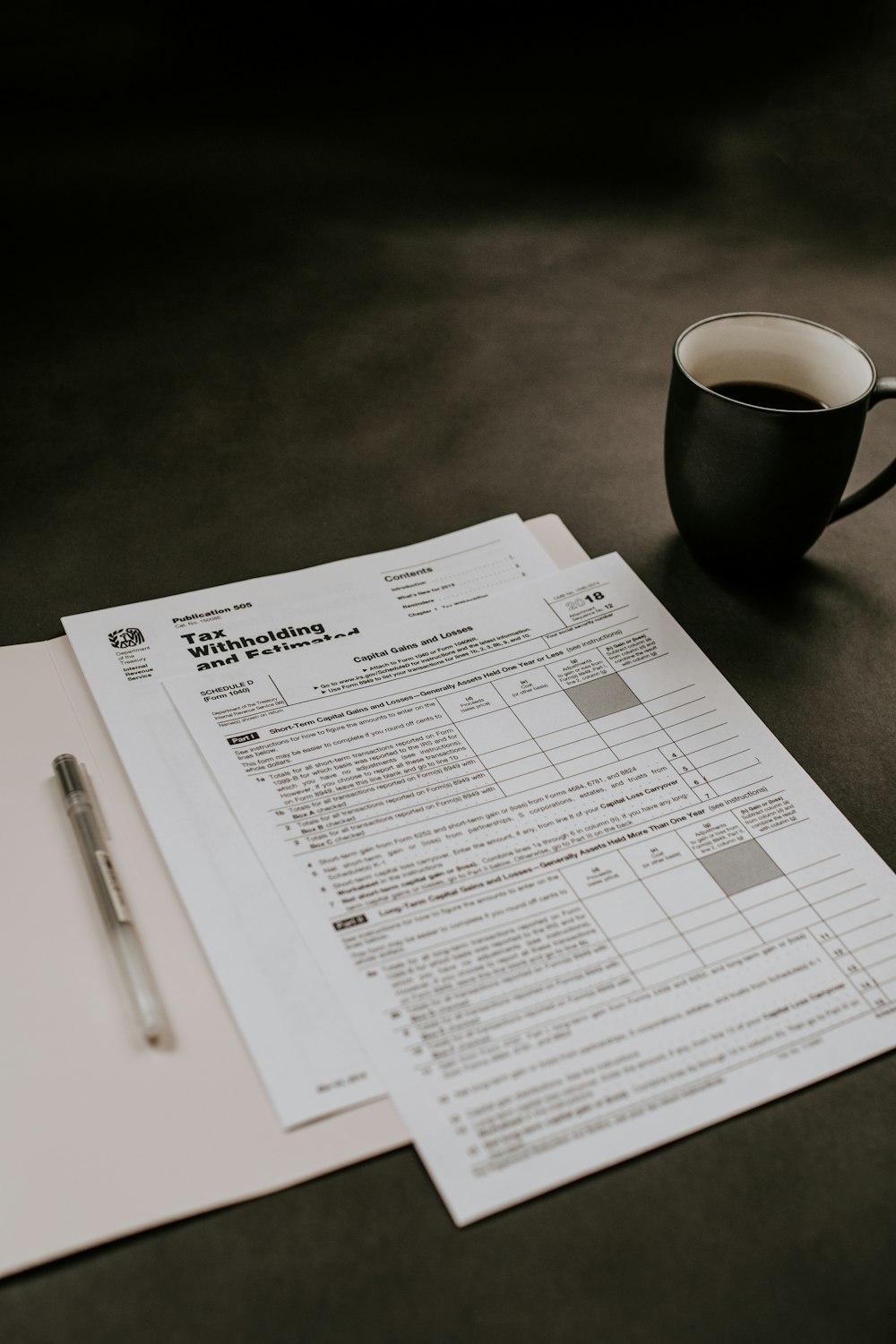 black ceramic mug beside white printer paper