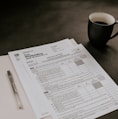 black ceramic mug beside white printer paper