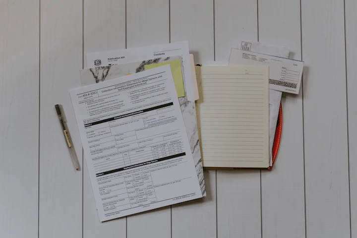 Financial forms, receipts and a notepad spread on a pale desk
