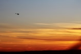 A helicopter prototype taking off during a field test at sunset.