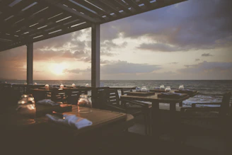 Mediterranean-style restaurant terrace with wine glasses and a sea view at sunset.
