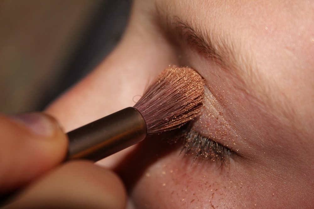 woman applying brown glittered eyeshadow