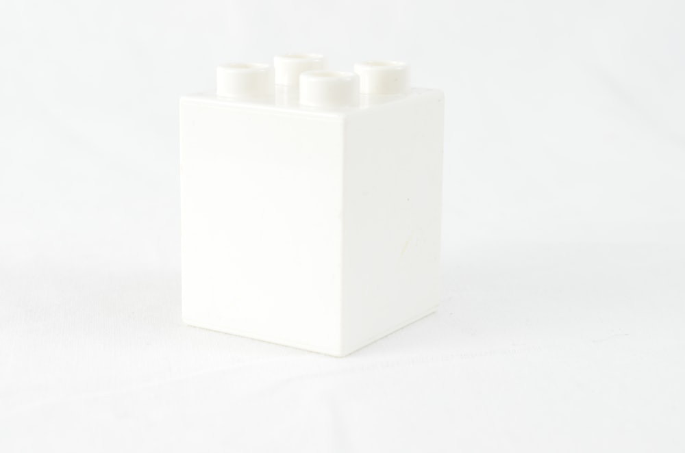 a white box with four white candles in it