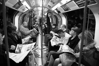 grayscale photo of people sitting on train chairs