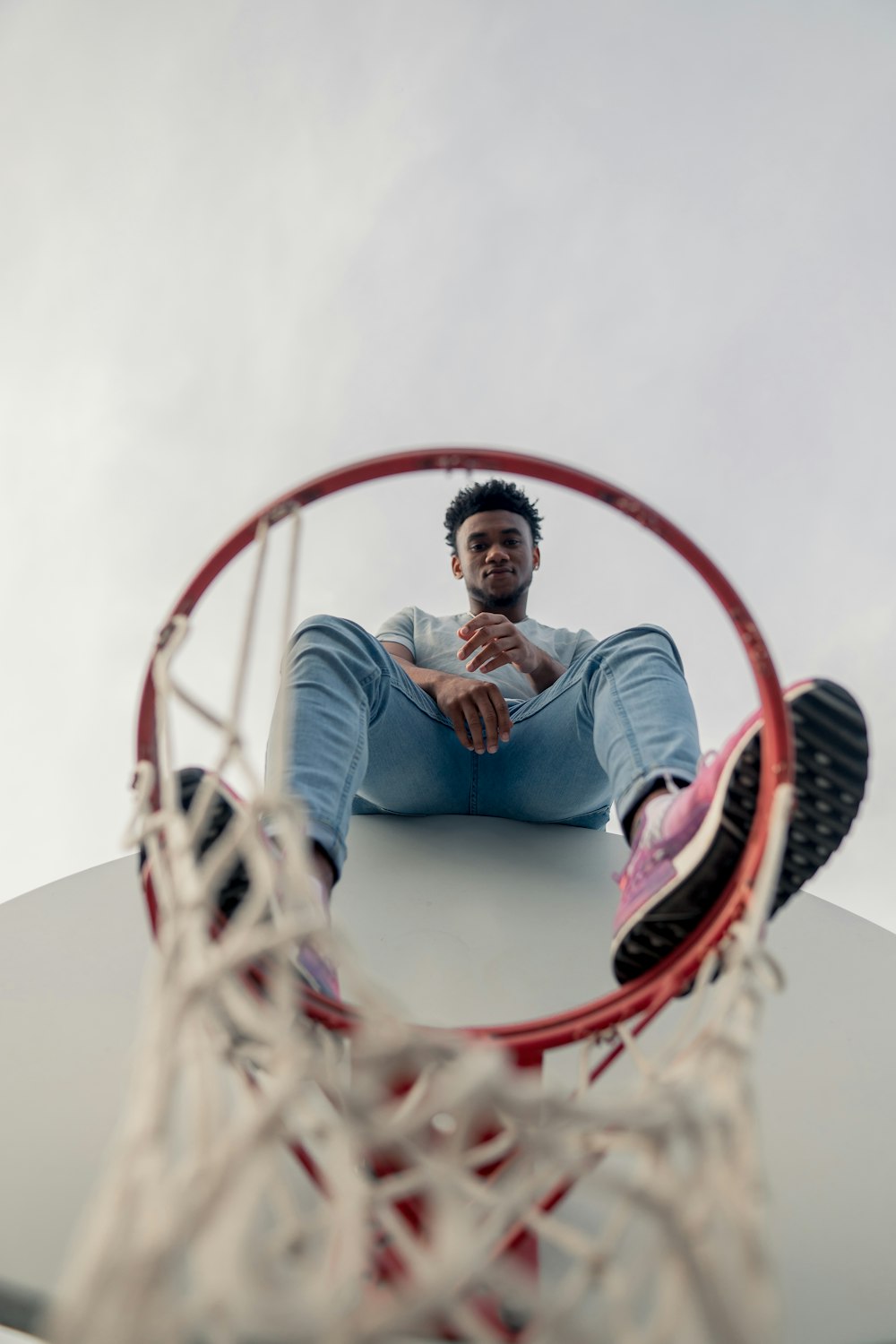 man sitting at the top of basketball hoop