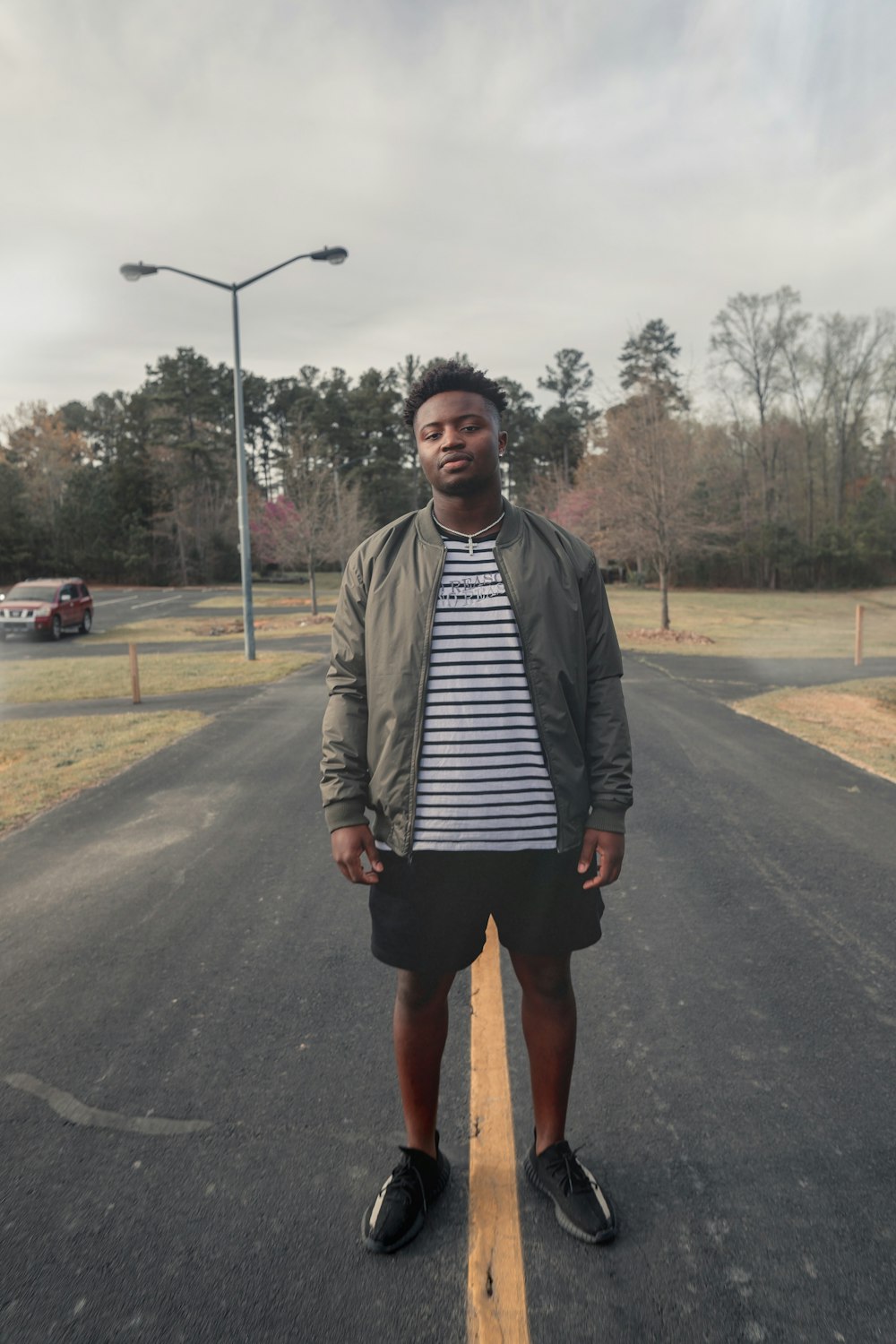 man in brown jacket standing on road