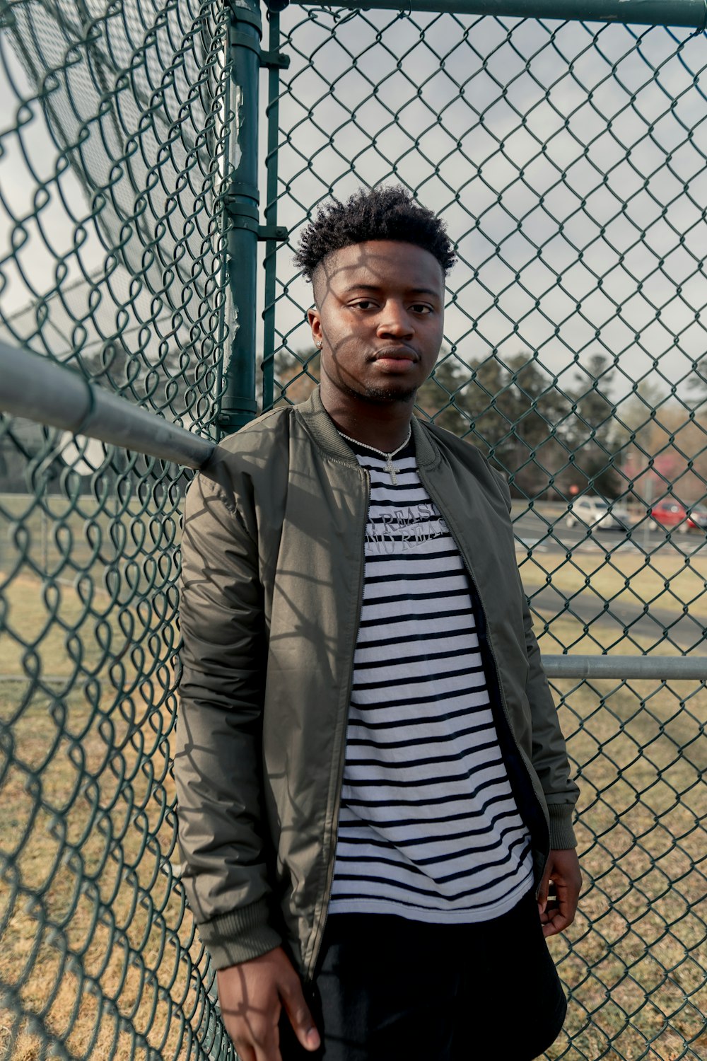 man leaning on chain link fence