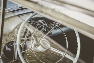 The dashboard view inside a vintage car, with a glimpse of the steering wheel and speedometer.