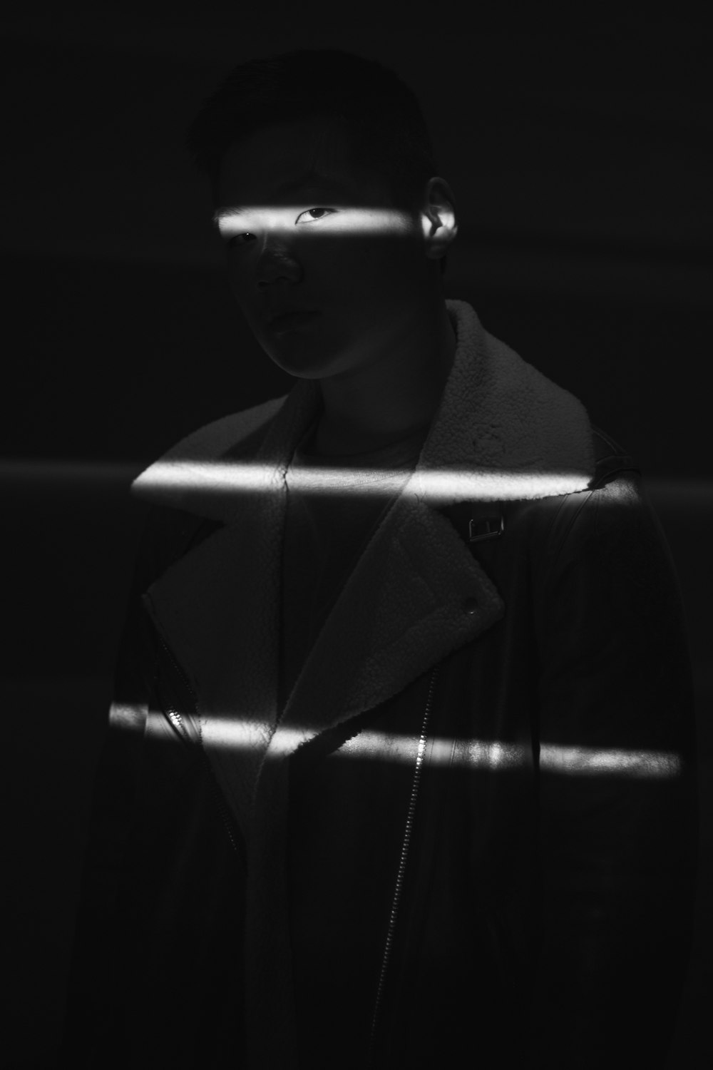 um homem parado em um quarto escuro com os olhos fechados