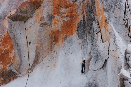 A climber scaling a colorful rock wall outdoors.