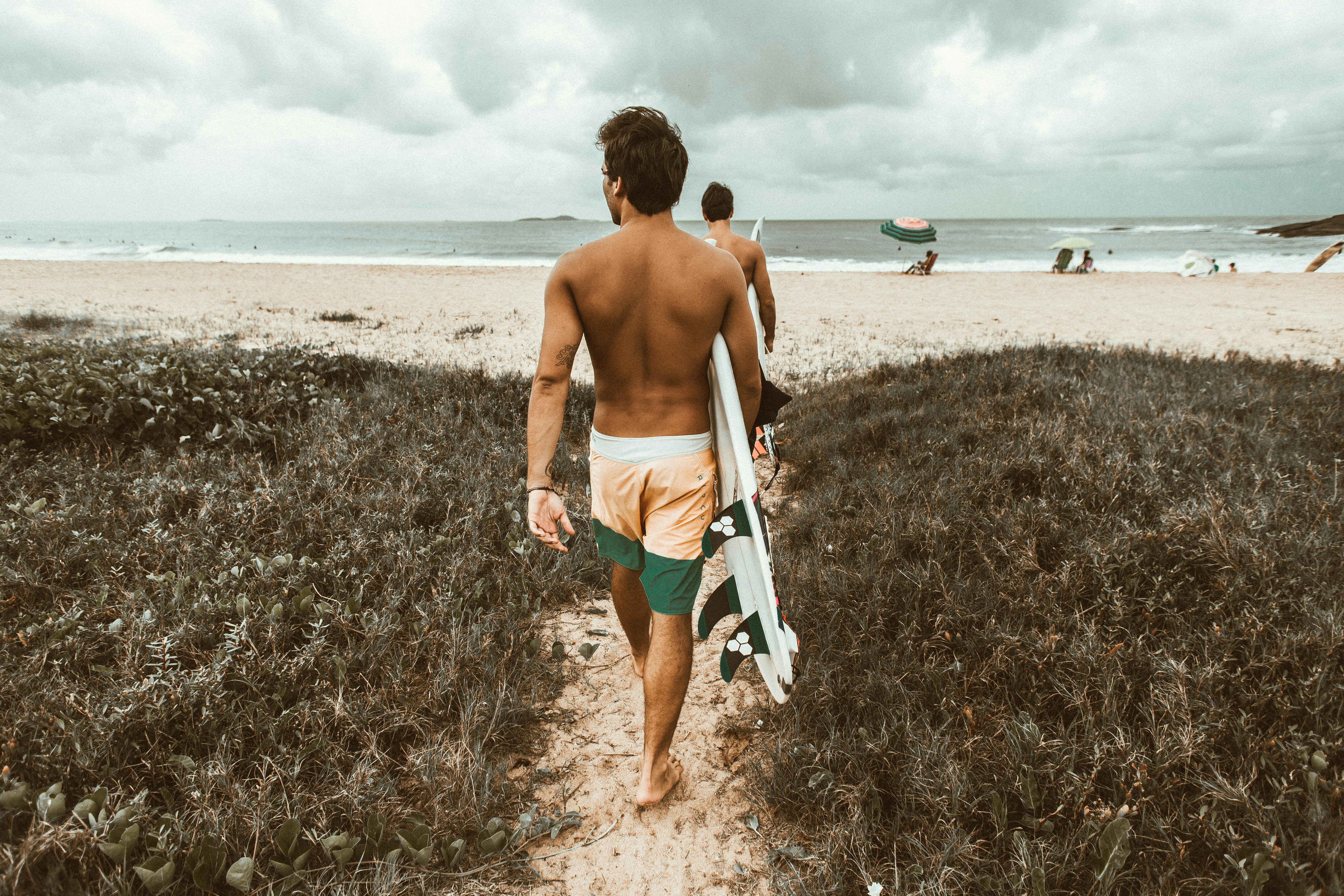 man walking to beach with a surfboard