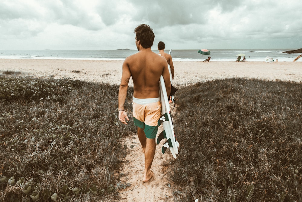 homme portant une planche de surf