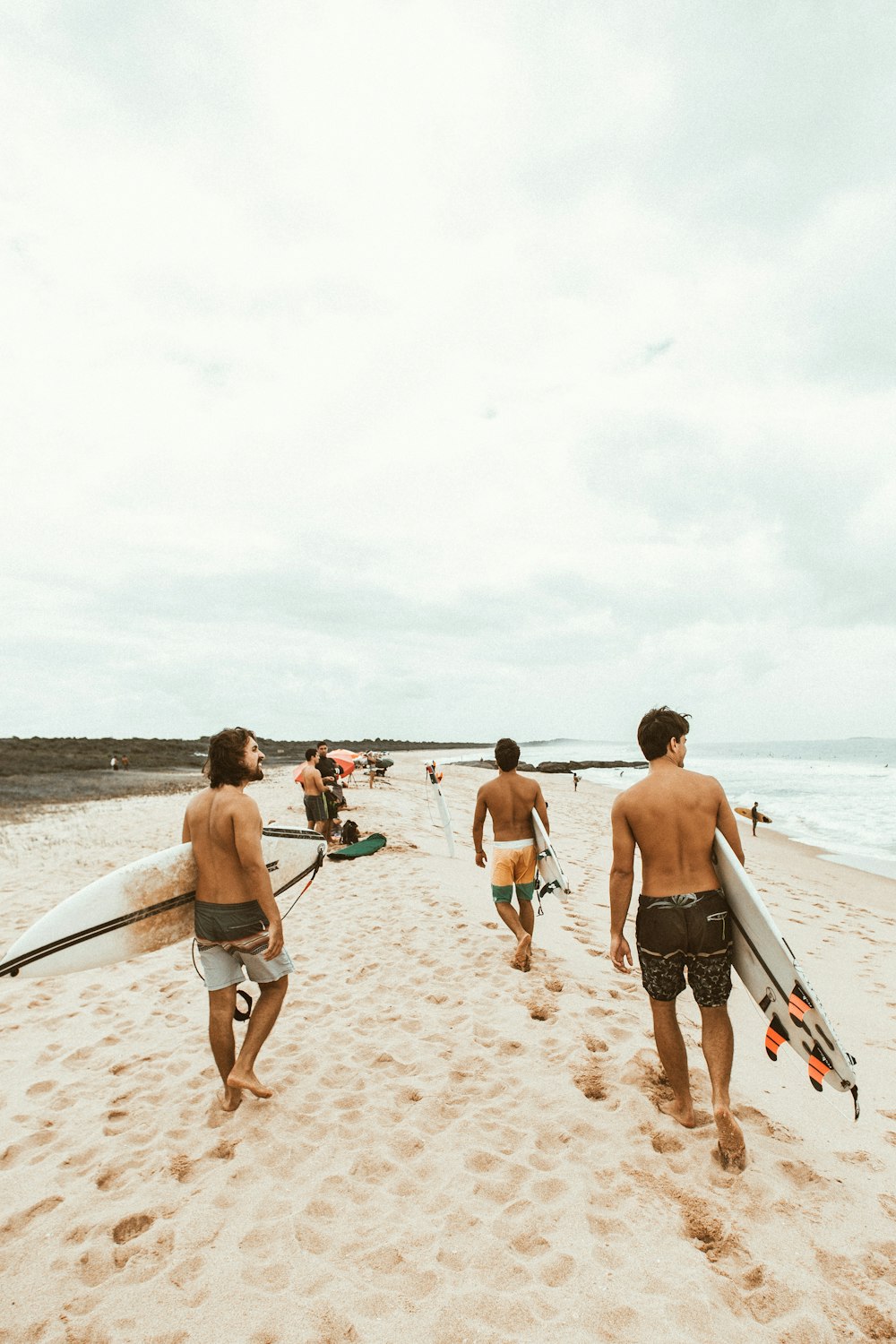 Gruppe von Surfern, die am Meer spazieren gehen