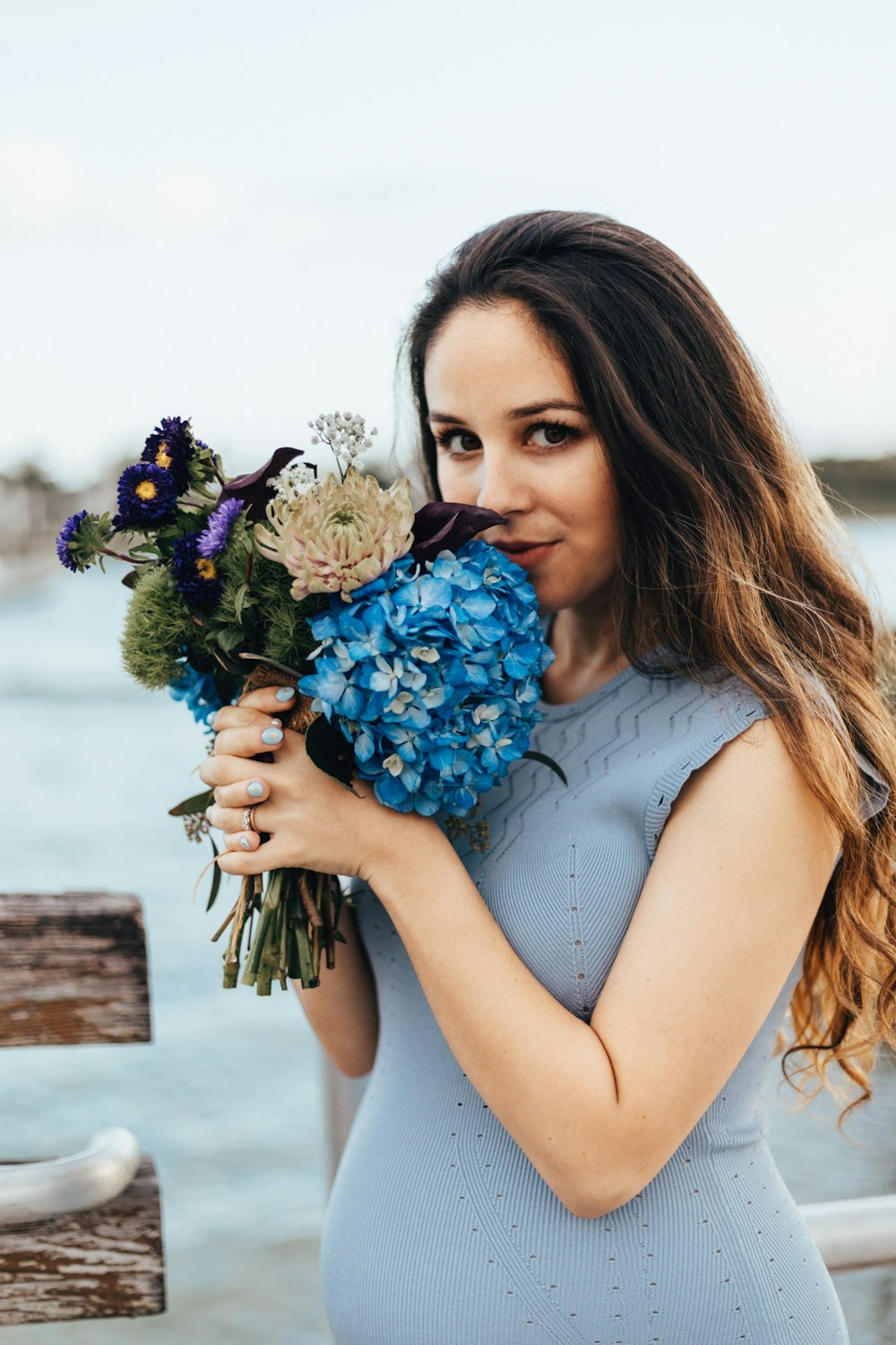 vestido azul das mulheres sem mangas segurando flores