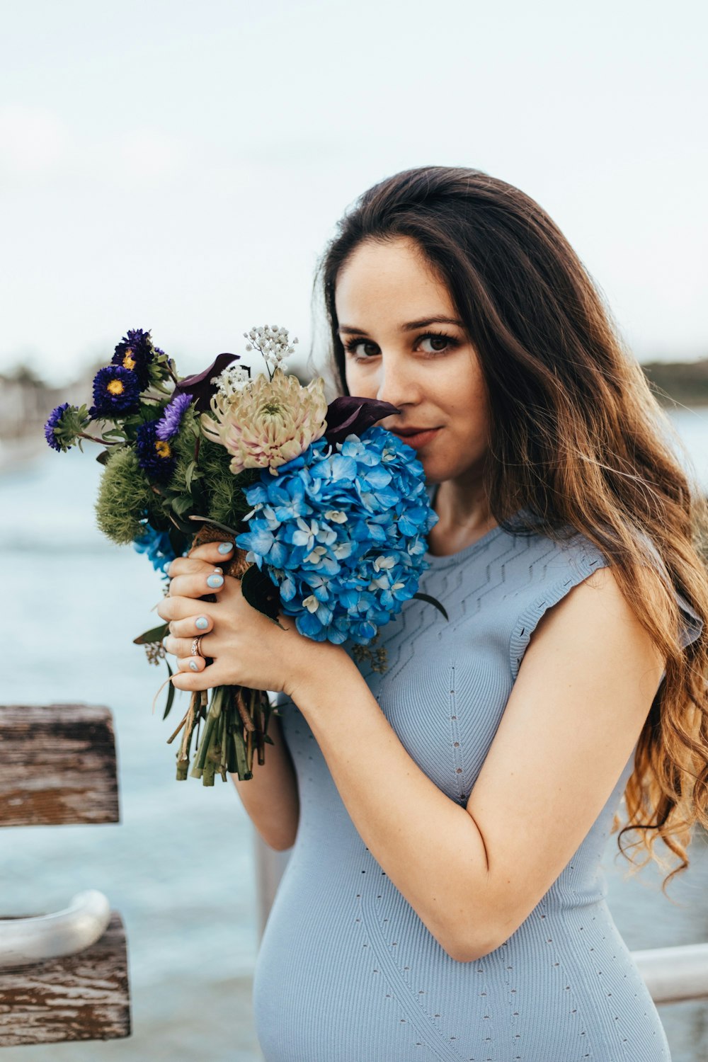 花を握る女性の青いノースリーブドレス