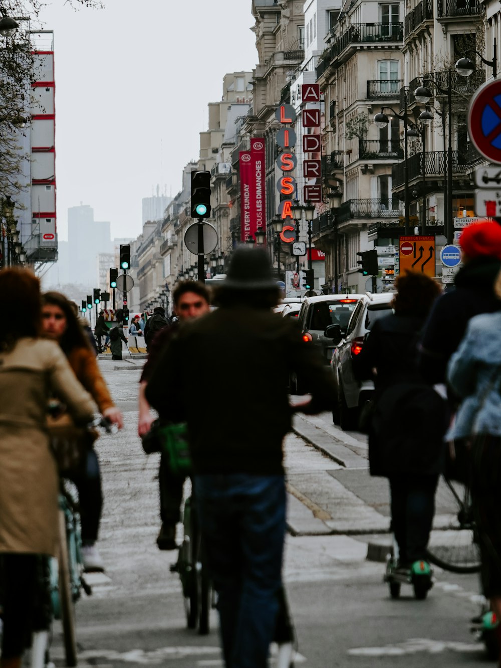 people cycling and riding kick scooter near road during daytime