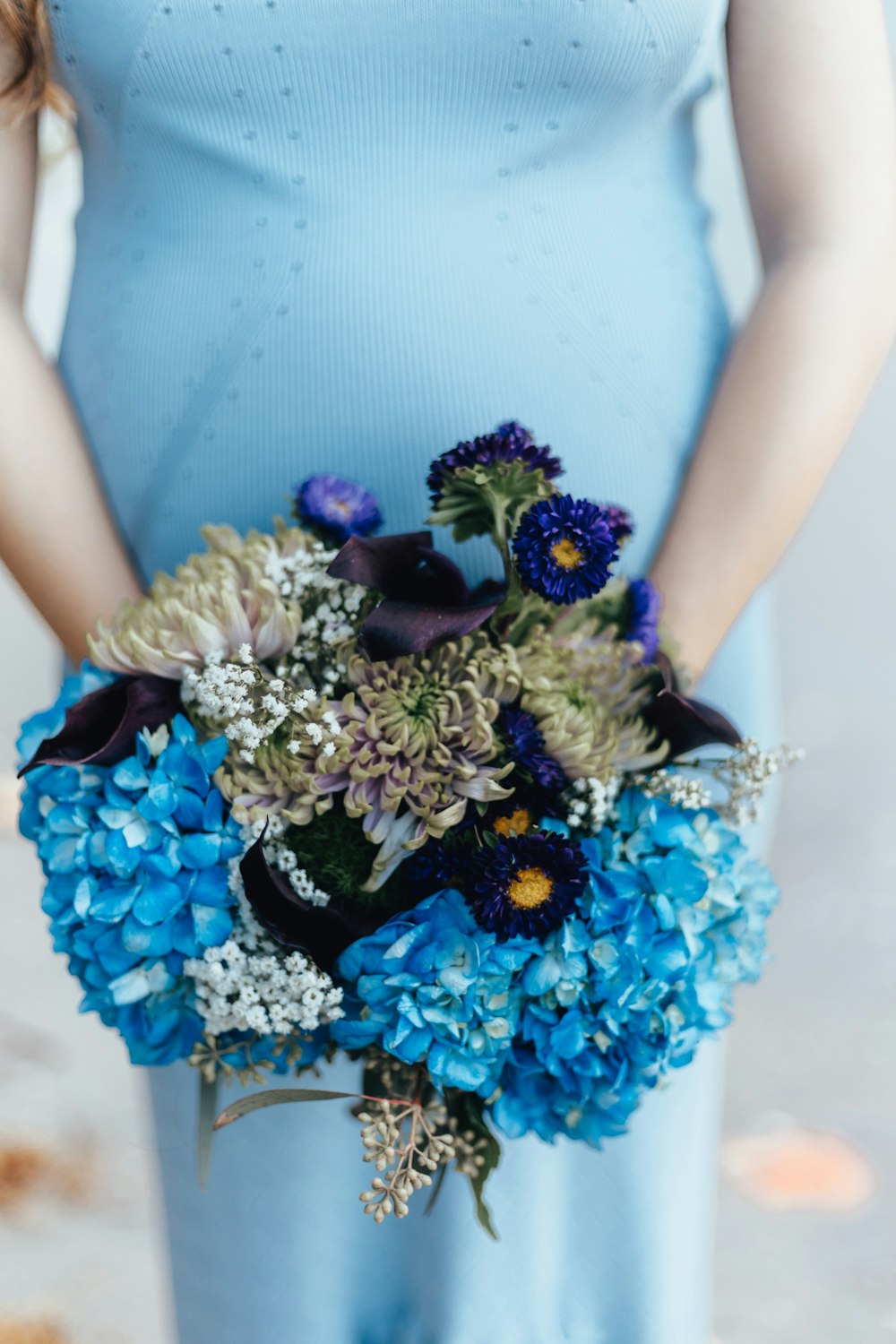person wearing blue dress holding flowers