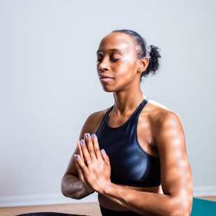 woman wearing black sports bra meditating