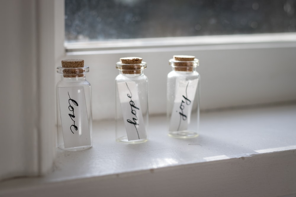 three love happy joy texts in vials beside window